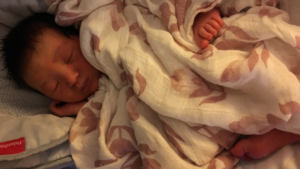 Baby girl asleep under white and pink blanket