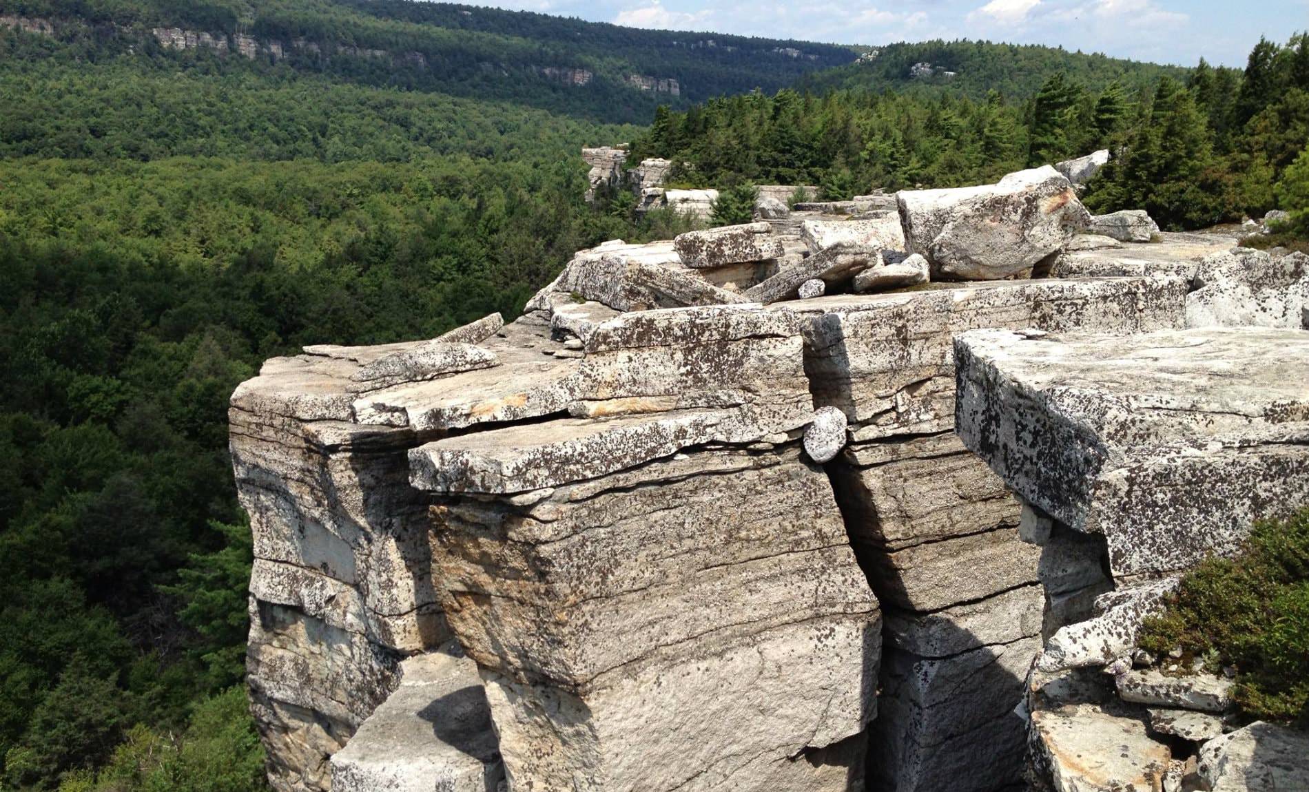 Rocky outcroppings overlooking miles of green hills covered in pine trees and blue skies