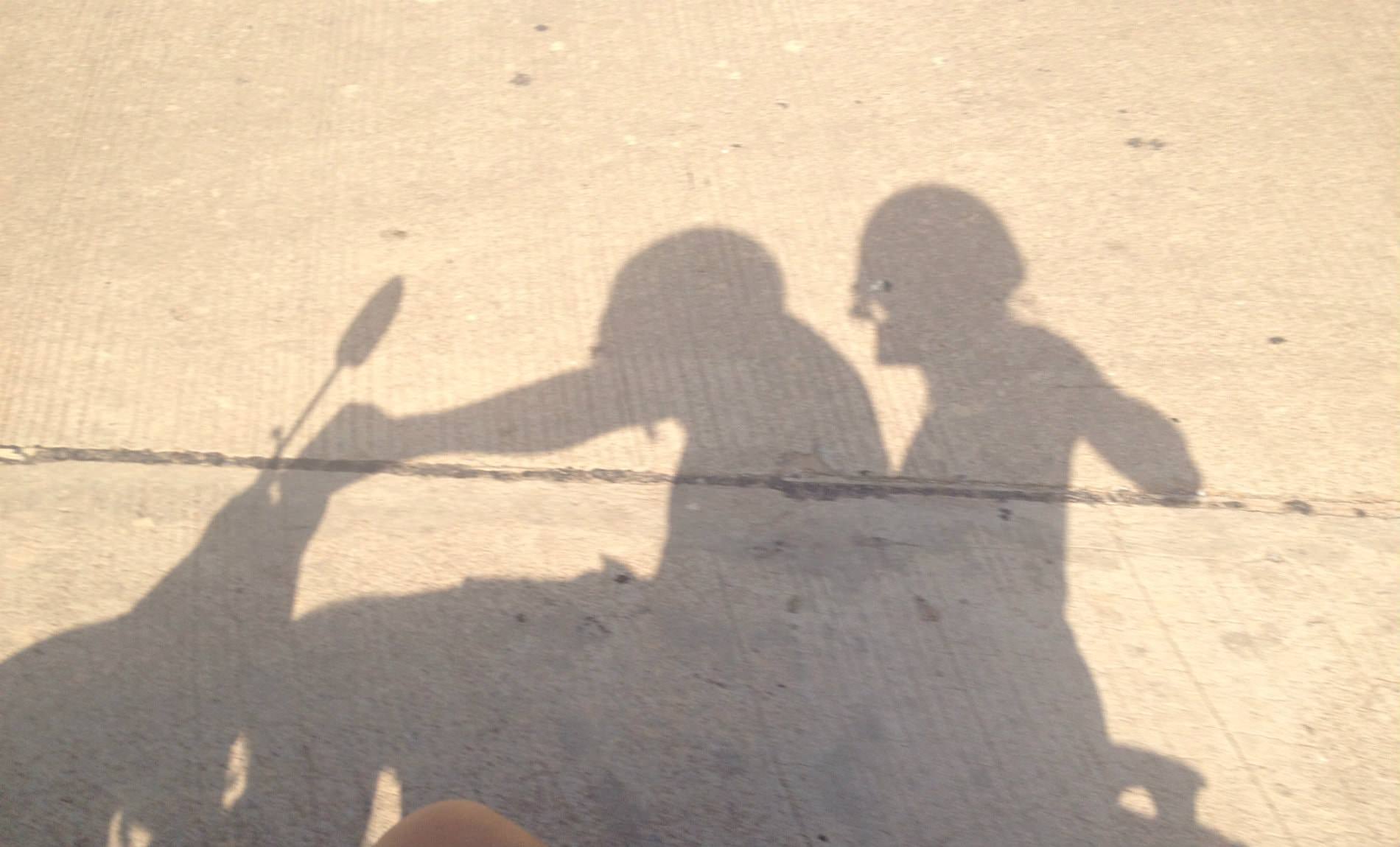 Gray shadow on concrete of two people riding a motorcycle