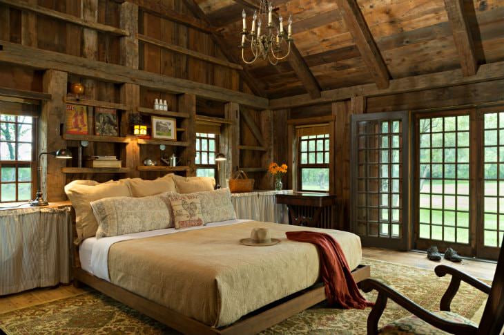 Vaulted rustic wood plank room with exposed beams, double-hung windows and French door, and large bed with tan bedding